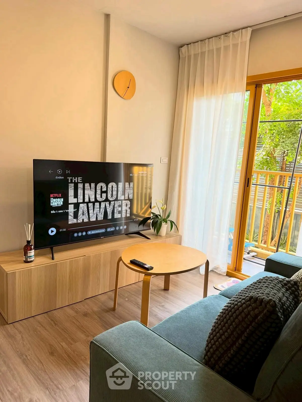 Cozy living room with modern decor and large TV, featuring a view of the balcony.