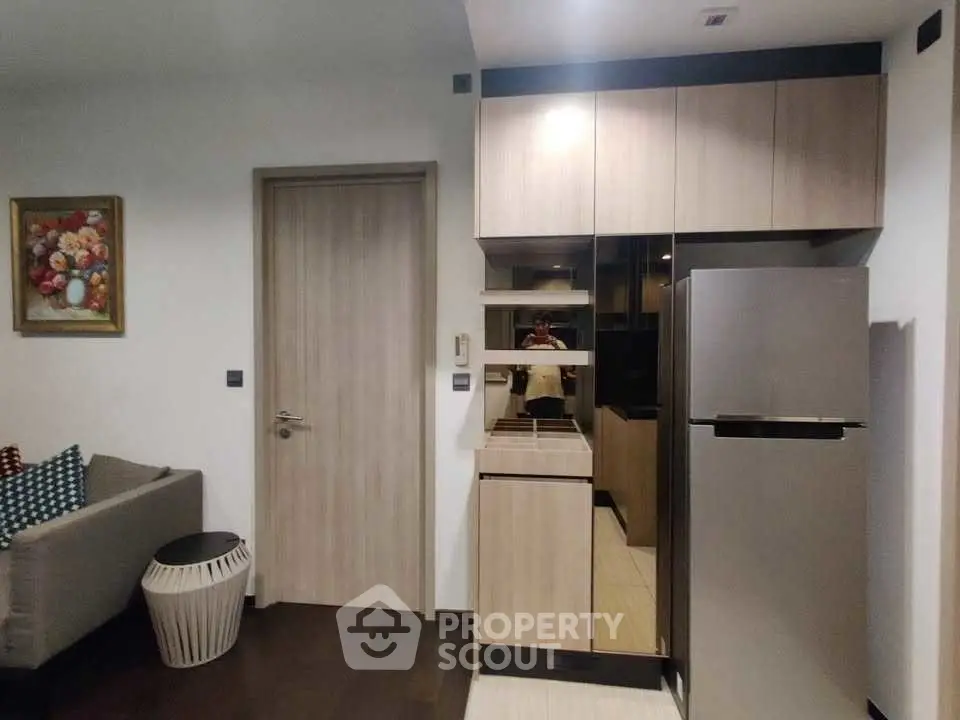 Modern kitchen with sleek cabinetry and stainless steel fridge in cozy apartment.