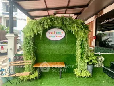 Charming garden entrance with lush greenery and cozy seating area, perfect for relaxation and welcoming guests.