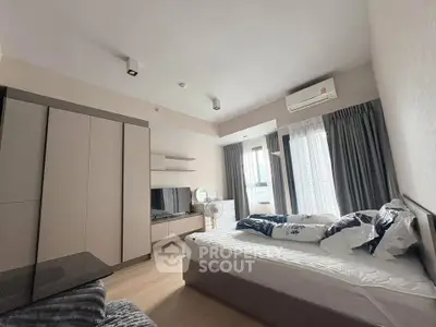 Modern bedroom with stylish decor and ample natural light, featuring a cozy bed and sleek furniture.