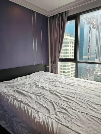 Modern bedroom with large windows offering stunning city views in a high-rise apartment.