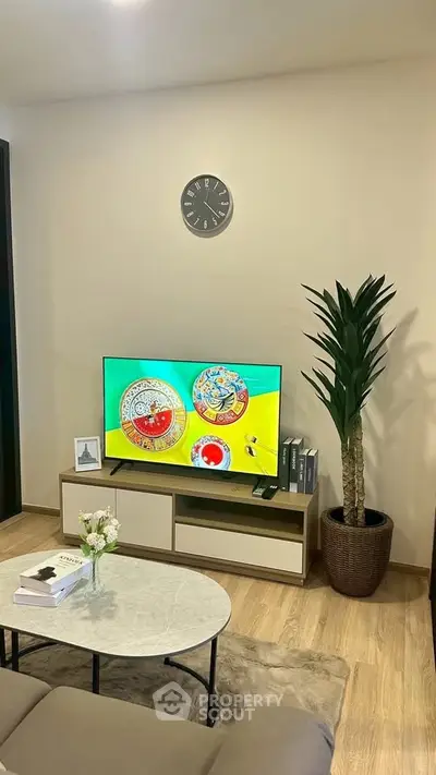 Modern living room with stylish decor, TV, and indoor plant, perfect for relaxation and entertainment.