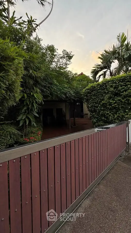Charming garden entrance with lush greenery and wooden fence, perfect for a serene home setting.