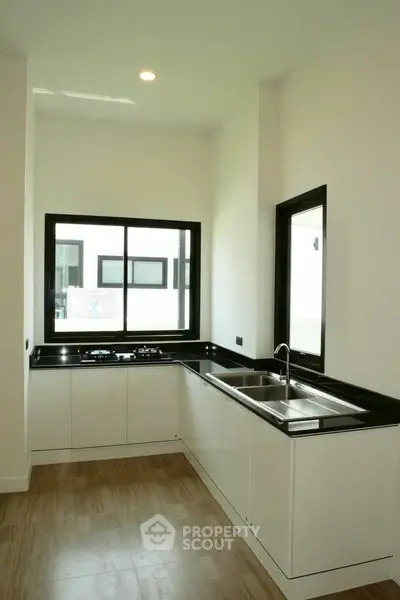 Modern kitchen with sleek black countertops and large windows for natural light.