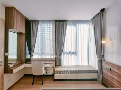 Modern study room with elegant wooden furniture and large window with sheer curtains.