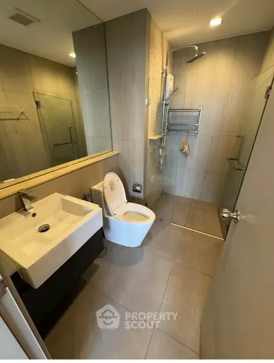 Modern bathroom with sleek fixtures and glass shower enclosure in contemporary apartment.