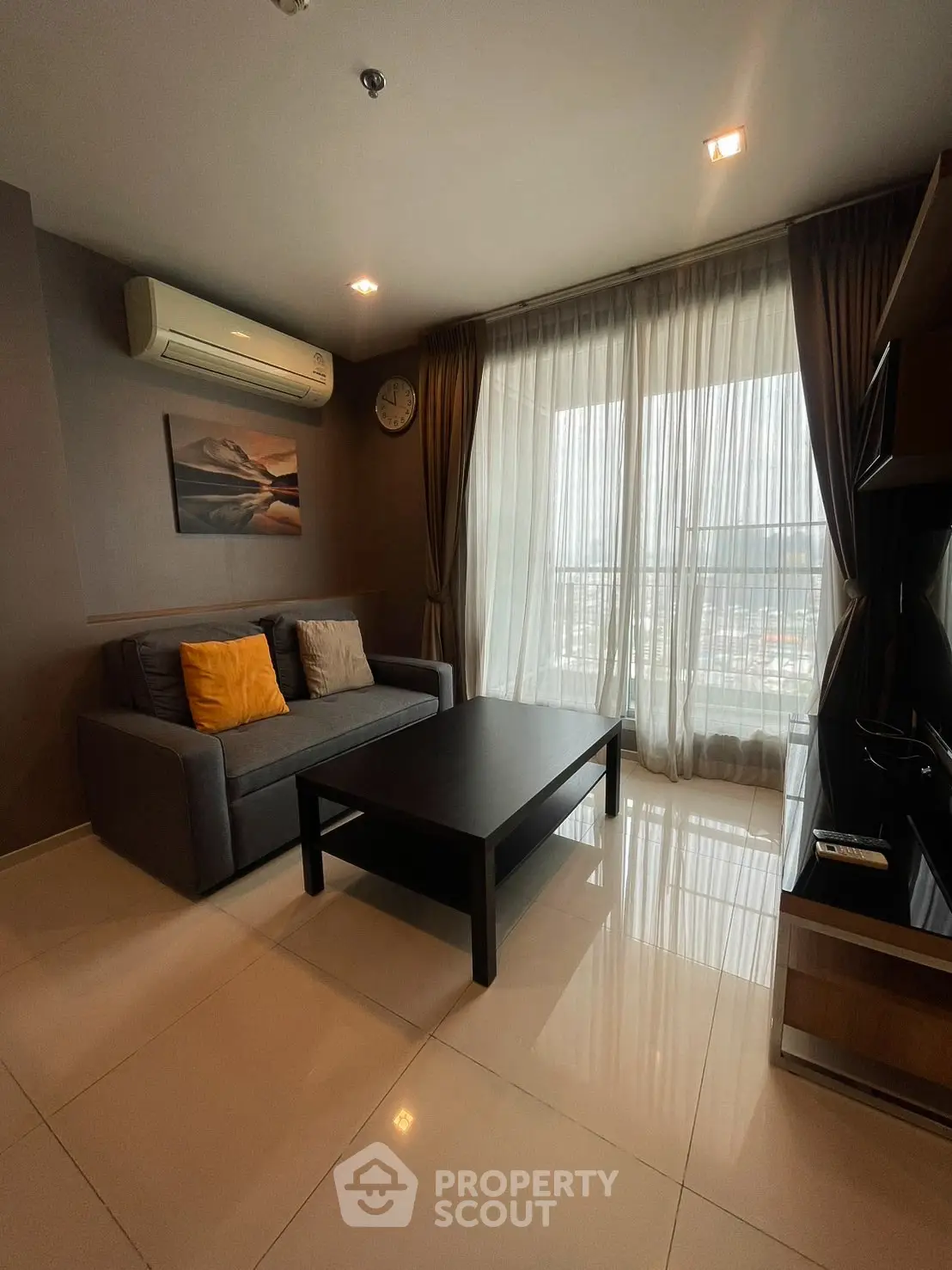 Modern living room with sleek furniture and large window offering natural light.