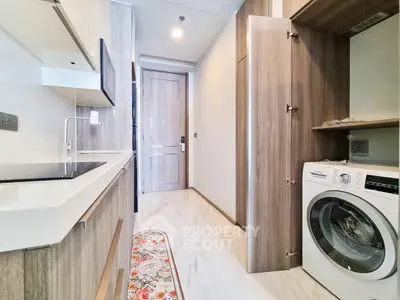 Modern kitchen with sleek appliances and washing machine in compact layout