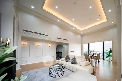 Luxurious living room with high ceilings and elegant decor, featuring a stunning view through large windows.