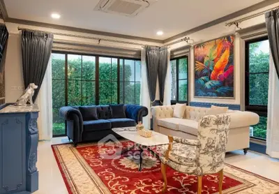 Elegant living room with plush sofas, vibrant artwork, and large windows overlooking lush greenery.