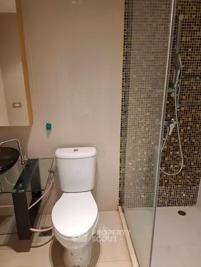 Modern bathroom with glass shower and sleek fixtures in contemporary apartment.