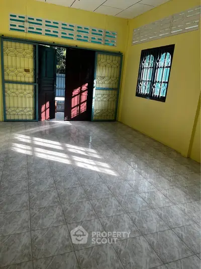 Spacious room with tiled flooring and large windows for natural light.