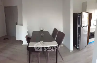 Modern dining area with sleek table and chairs next to a contemporary kitchen.