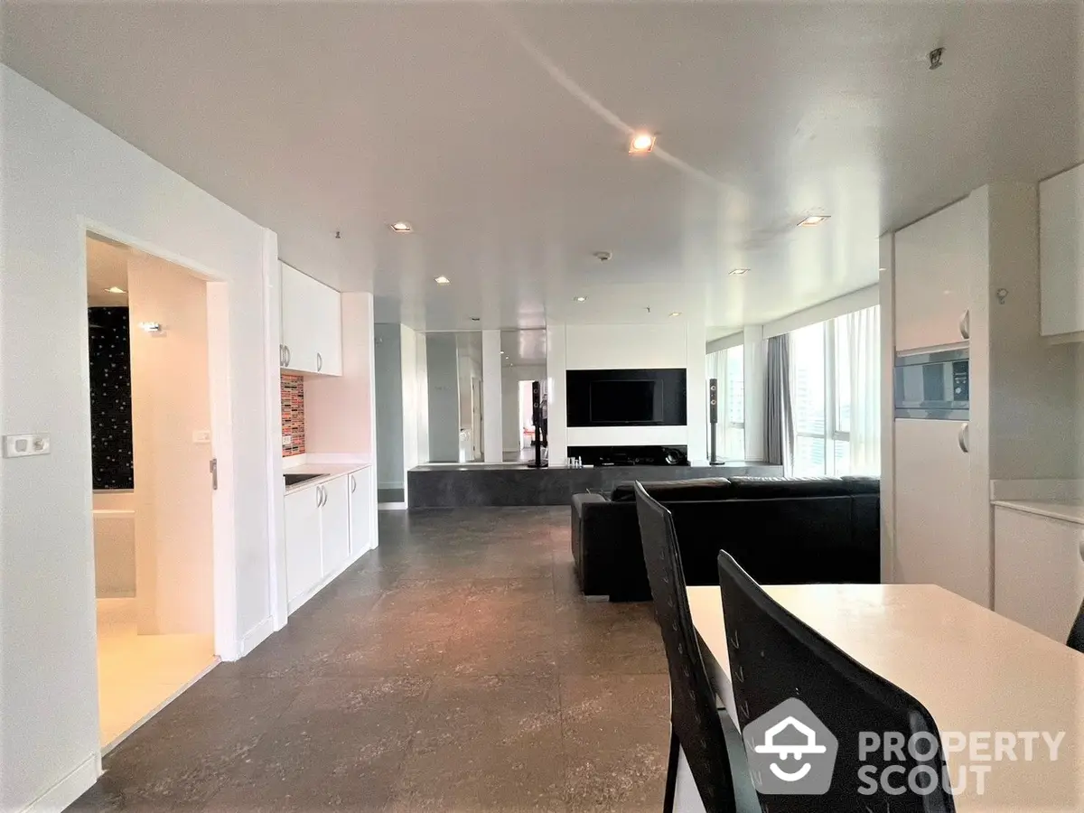 Spacious open-plan living area with sleek modern kitchen, ample natural light, and contemporary furnishings, perfect for entertaining and relaxation.