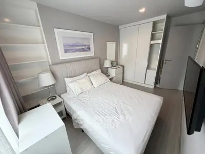 Modern bedroom with sleek white furniture and cozy bed in stylish apartment.