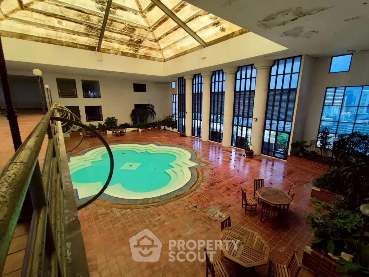 Stunning indoor pool area with skylight and elegant seating, perfect for relaxation and entertainment.