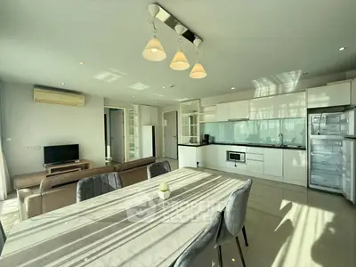 Spacious modern open-plan living room and kitchen with natural light and elegant furnishings.