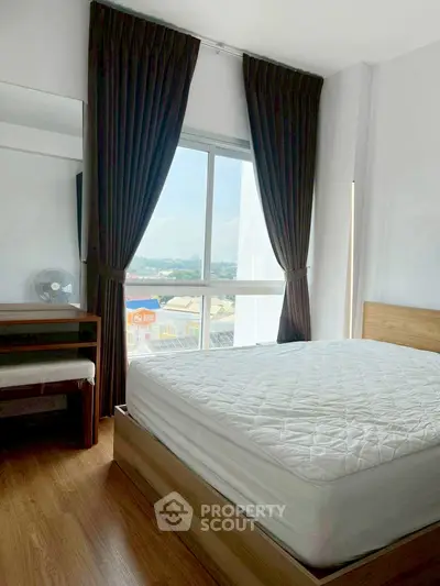 Bright bedroom with large window and wooden flooring, offering a serene view.