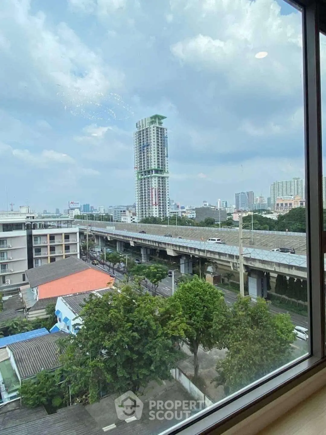 Stunning urban view from high-rise window overlooking cityscape and greenery.