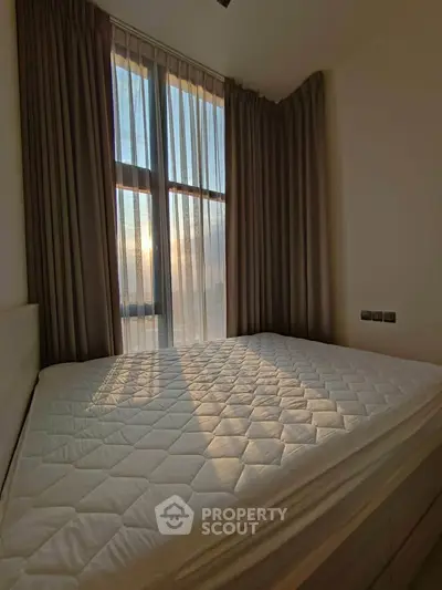 Spacious bedroom with large window and elegant curtains, offering abundant natural light and a serene atmosphere.