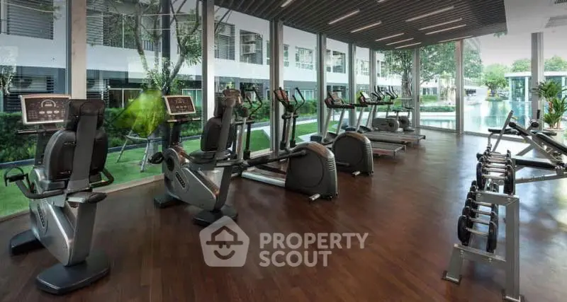Modern gym with state-of-the-art equipment and pool view in luxury apartment complex.