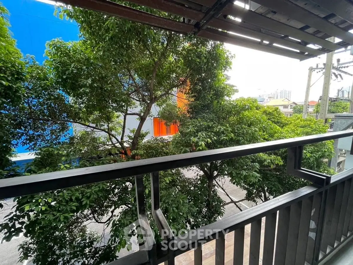 Spacious balcony with lush greenery and urban view, perfect for relaxation.