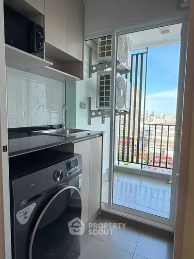 Modern kitchen with balcony view and washing machine in urban apartment