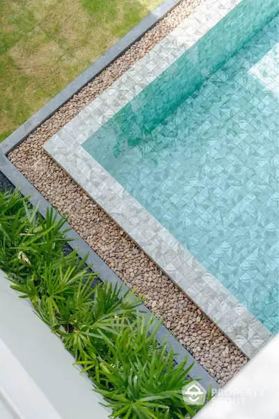 Luxurious modern pool with elegant stone border and lush greenery