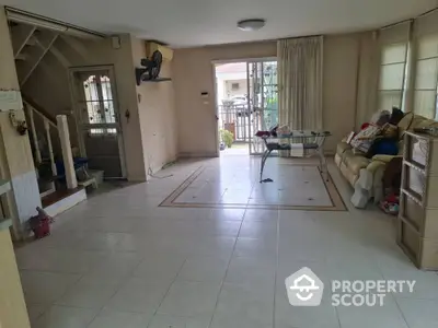 Spacious living room with tiled flooring and natural light in a cozy home.