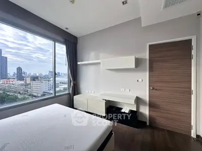 Modern bedroom with city view, featuring sleek furniture and large windows for natural light.