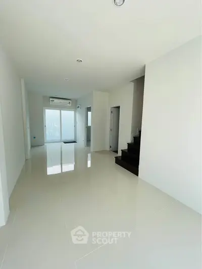 Spacious modern living room with sleek white tiles and staircase, perfect for contemporary living.