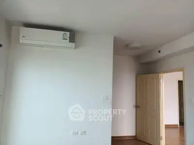 Minimalist room with air conditioning and open door, showcasing clean lines and neutral tones.