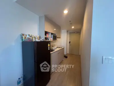 Modern compact kitchen with sleek cabinetry and black fridge in a cozy apartment.