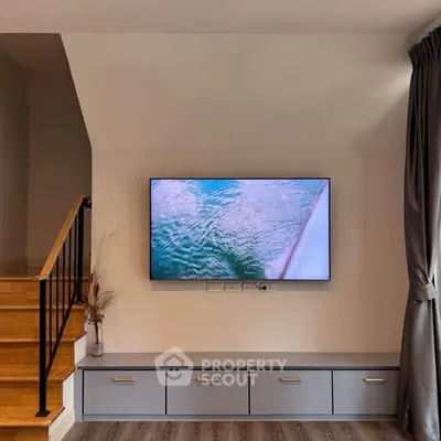 Modern living room with wall-mounted TV and stylish staircase