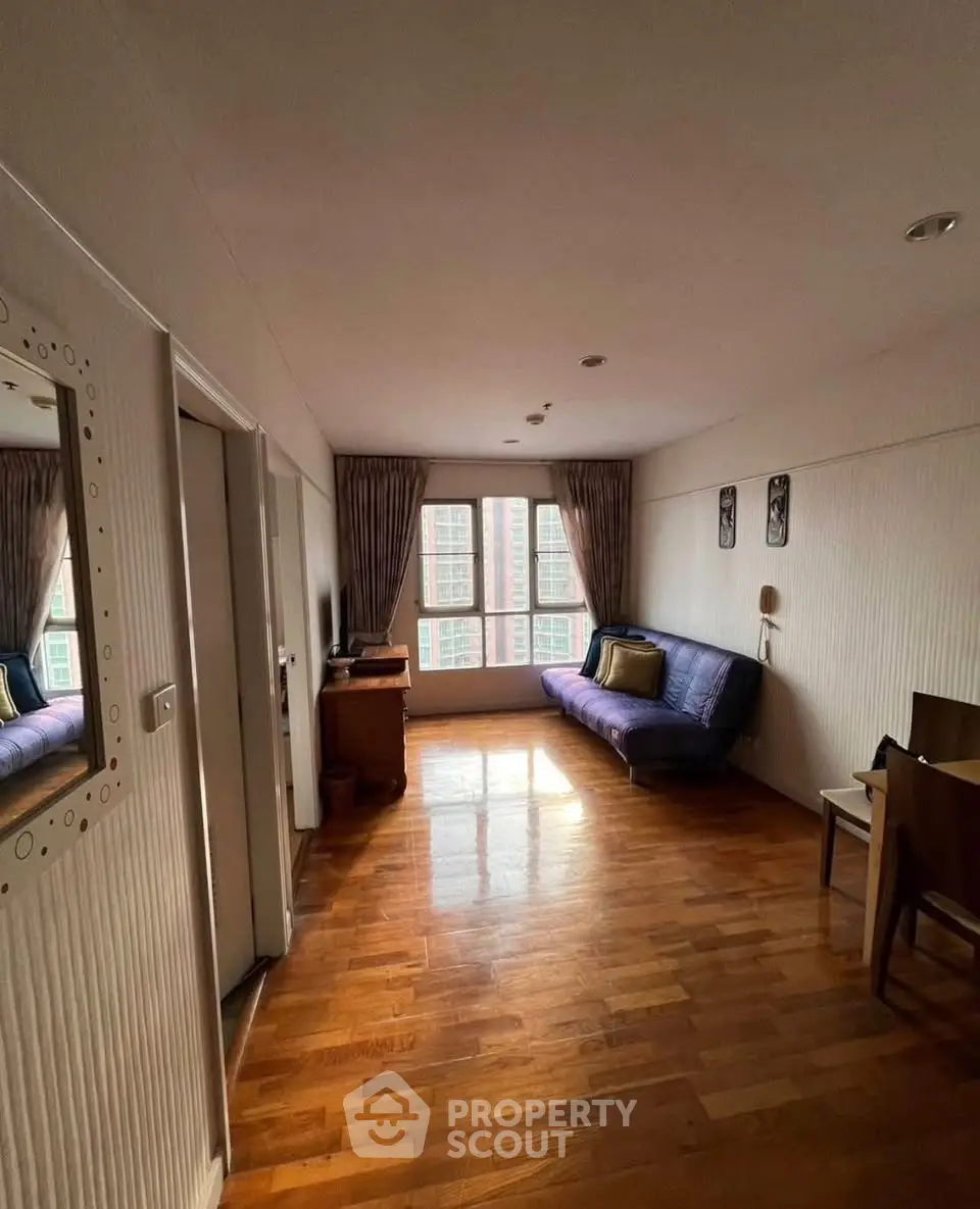 Cozy living room with wooden flooring and large window, perfect for relaxation.