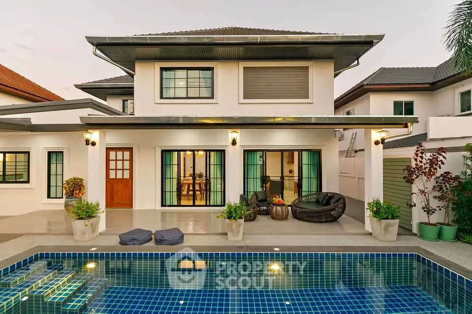 Stunning modern house with pool and elegant outdoor seating area at sunset.