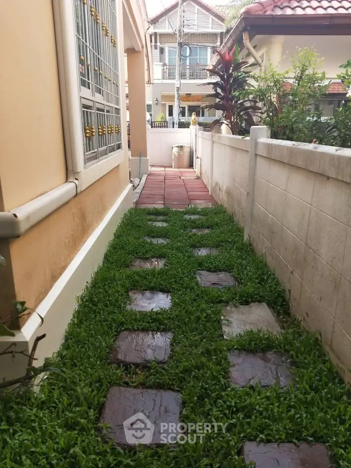 Charming garden pathway with lush greenery and stepping stones leading to a cozy home entrance.
