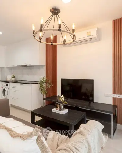 Modern living room with stylish chandelier, sleek kitchen, and cozy decor in a contemporary apartment.