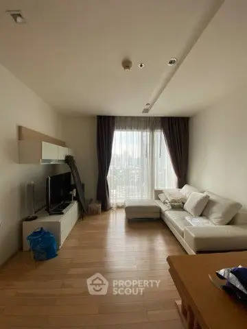 Spacious living room with modern decor and large window offering city views.