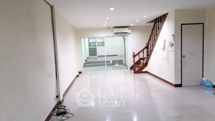 Spacious open-plan living area with staircase and air conditioning