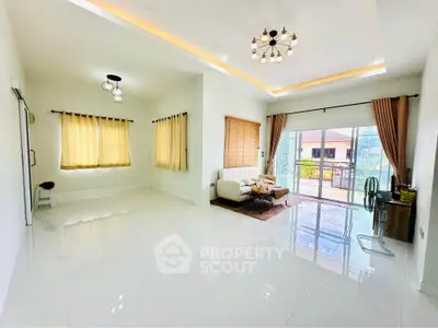 Spacious living room with modern lighting and large windows opening to a balcony with a view.