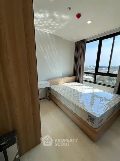 Bright bedroom with large window and modern furnishings, offering a stunning view.