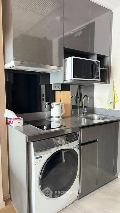 Modern compact kitchen with sleek cabinetry, built-in appliances, and washer-dryer combo in a stylish apartment.