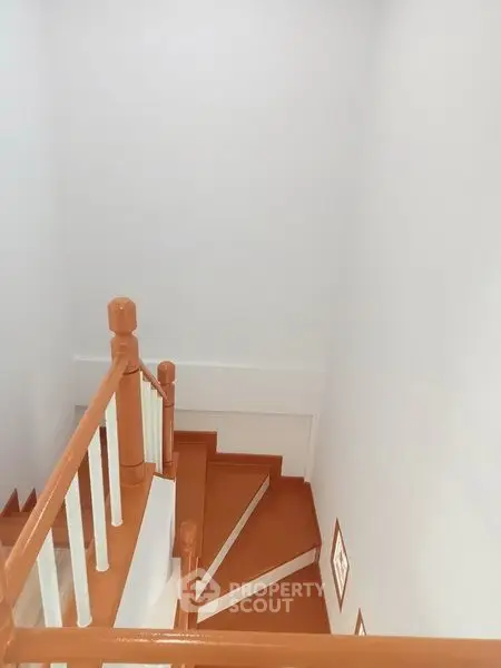 Modern staircase with wooden handrails and white walls in a contemporary home.