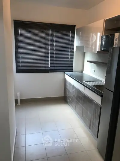 Modern kitchen with sleek cabinets and large window blinds, ideal for culinary enthusiasts.