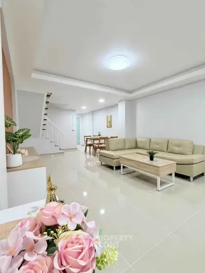 Spacious modern living room with elegant decor and open layout, featuring a cozy beige sofa and stylish dining area.