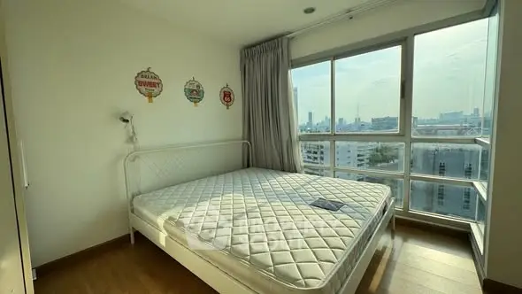 Bright bedroom with large windows offering stunning city views and ample natural light.