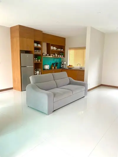 Spacious open-plan living room with modern kitchen and sleek gray sofa, perfect for contemporary living.
