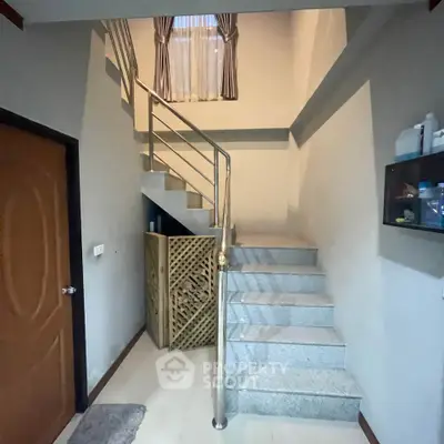 Charming interior staircase with modern railing and natural light, perfect for cozy home living.
