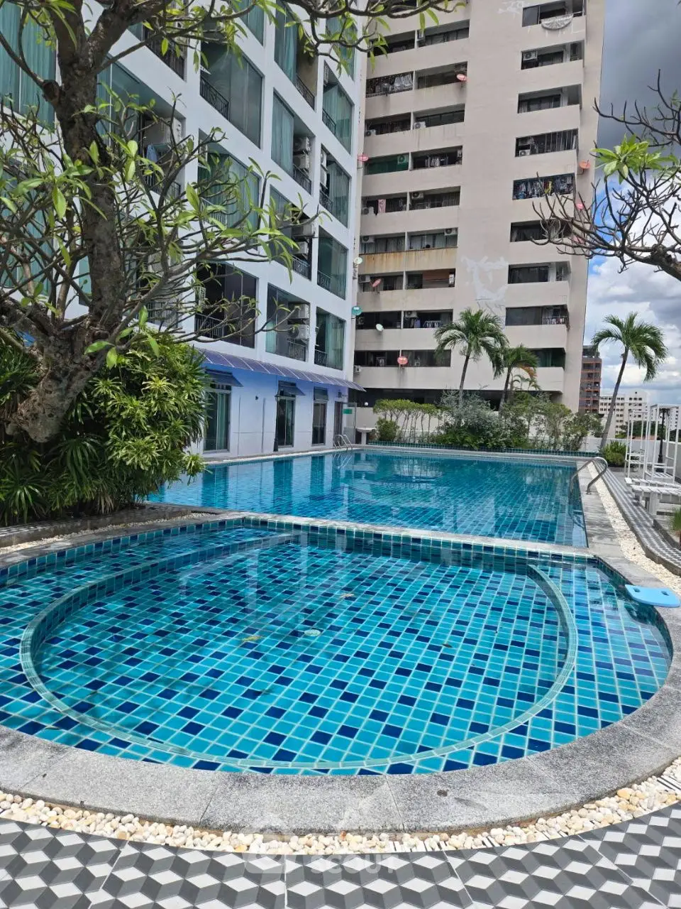 Luxurious residential pool area with modern design and cityscape view, perfect for relaxation.